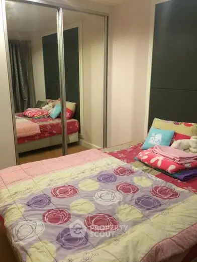 Cozy bedroom with mirrored closet doors and colorful bedding in modern apartment.