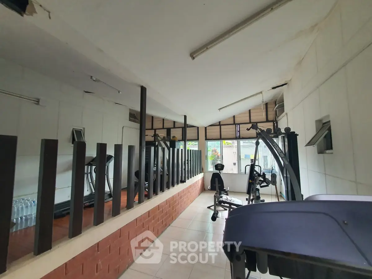 Spacious gym with modern equipment and large windows for natural light.