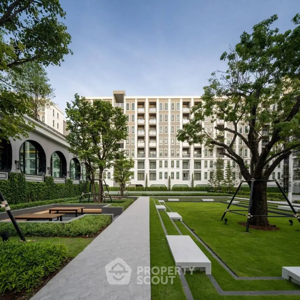 Luxurious modern apartment building with lush landscaped garden and seating area.