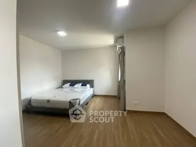 Spacious minimalist bedroom with wooden flooring and modern bed