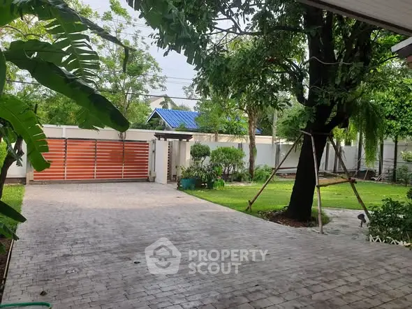 Spacious garden with paved driveway and lush greenery in a serene residential area.
