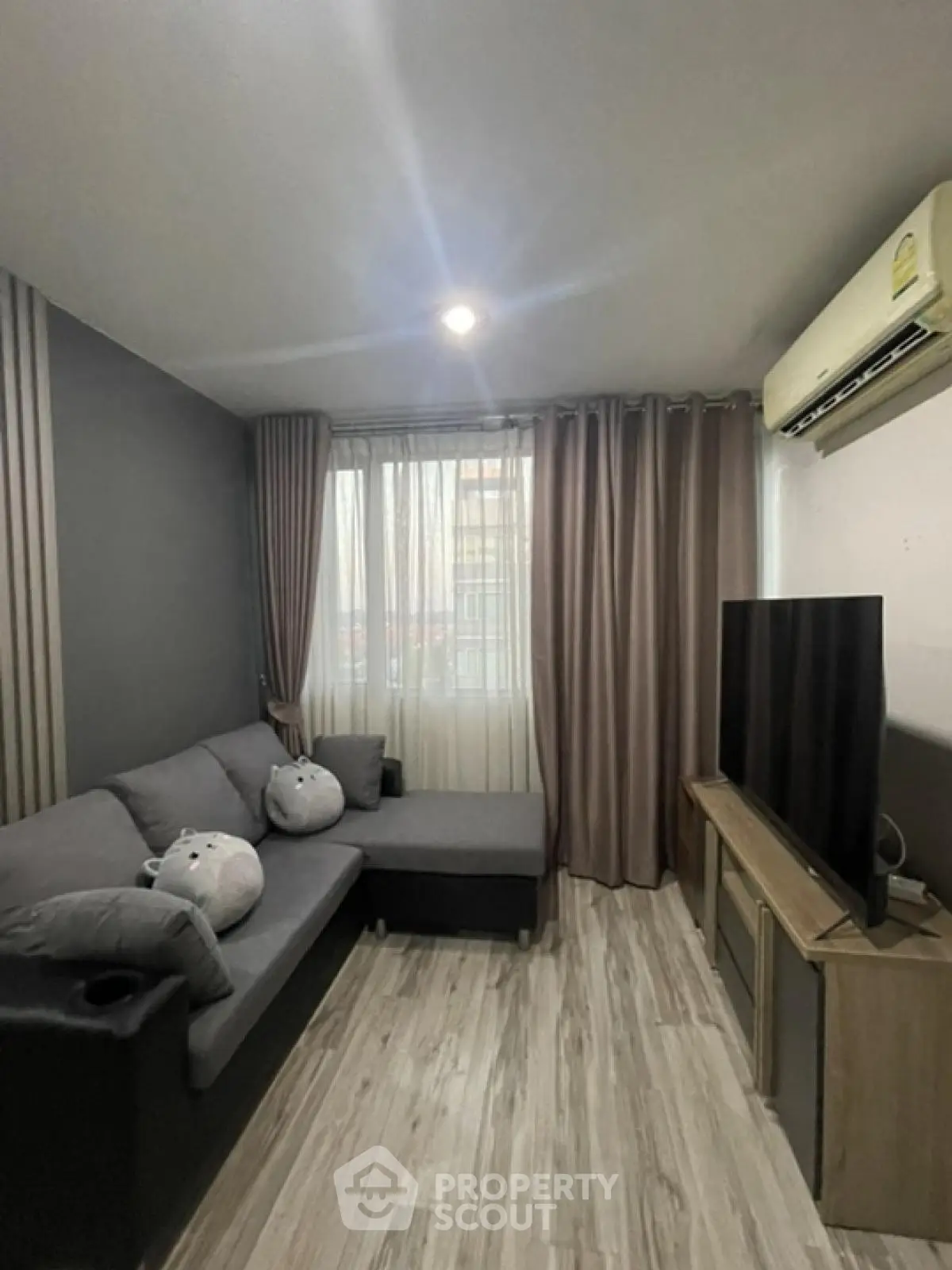 Modern living room with cozy gray sofa and large TV, perfect for relaxation.