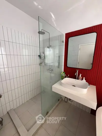 Modern bathroom with glass shower and red accent wall