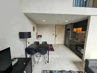 Modern open-plan living room with sleek kitchen and dining area in stylish apartment.