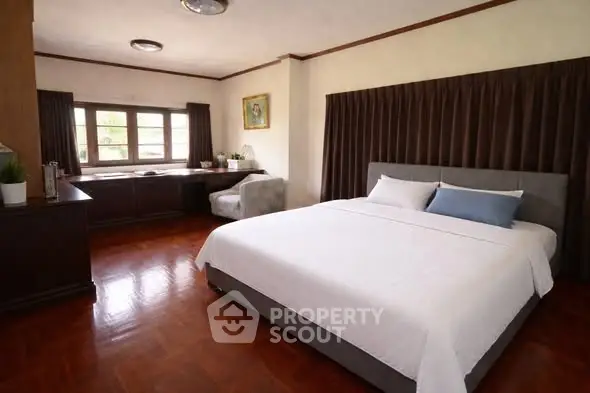Spacious bedroom with elegant decor and large window for natural light.