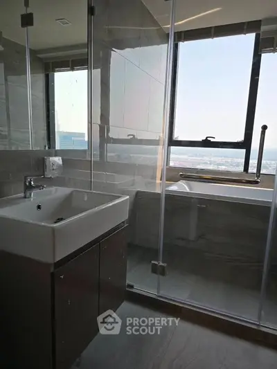 Modern bathroom with large window and sleek fixtures offering city views.
