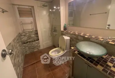 Modern bathroom with glass shower, stylish sink, and tiled accents.