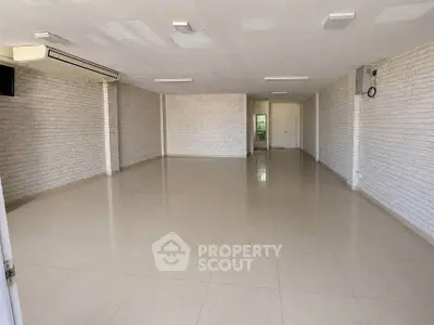 Spacious empty room with tiled flooring and white brick walls, ideal for customization.