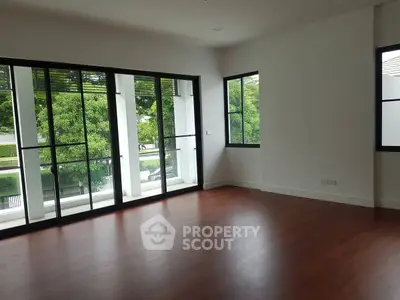 Spacious empty room with large windows and wooden flooring, perfect for customization.