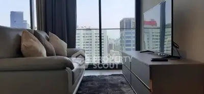 Modern living room with city view, featuring a cozy sofa and sleek TV setup.