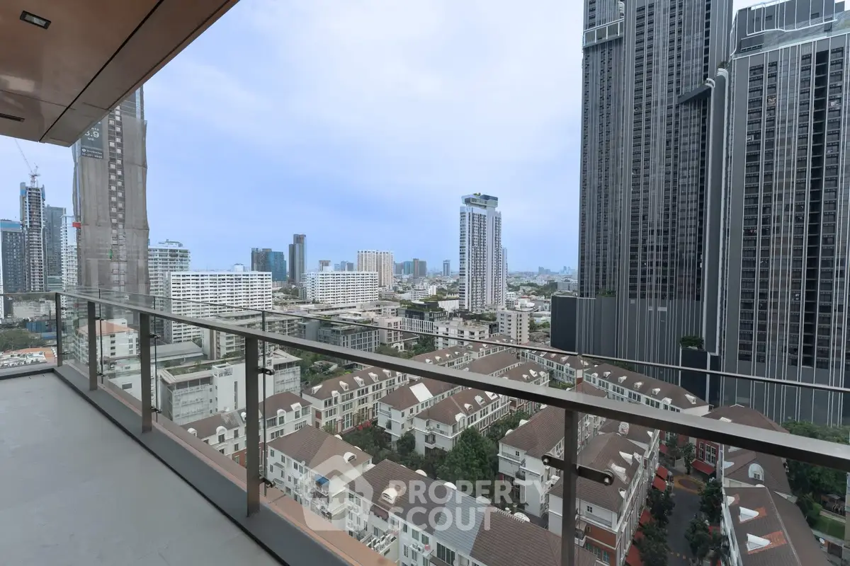 Stunning cityscape view from a modern high-rise balcony with glass railing.