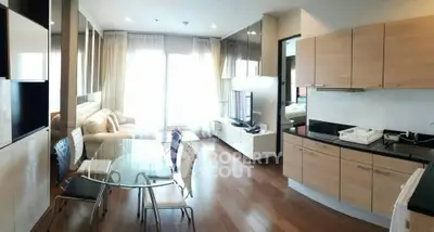 Modern open-plan living room with kitchen, featuring sleek furniture and natural light.