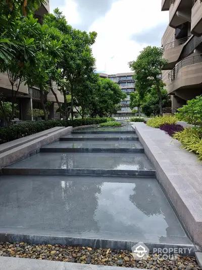 Luxurious modern apartment complex with lush gardens and serene water features.