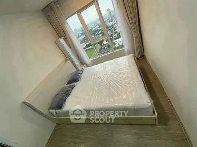Modern bedroom with large window offering stunning city view, featuring a cozy bed and elegant curtains.