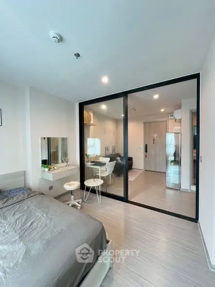 Modern bedroom with sliding glass doors leading to a cozy living area, featuring stylish decor.