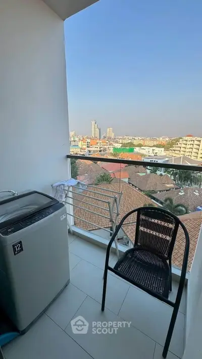 Charming balcony with city view, featuring a washing machine and seating area, perfect for relaxation.