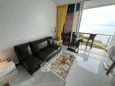 Stunning living room with ocean view and elegant decor, featuring a sleek black sofa and a charming balcony.