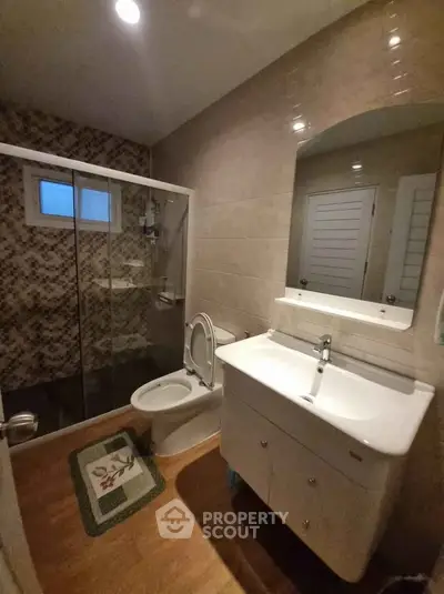 Modern bathroom with glass shower, stylish sink, and elegant tile design.