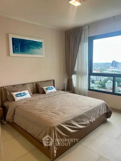 Spacious bedroom with large window offering stunning city views, modern decor, and cozy bedding.