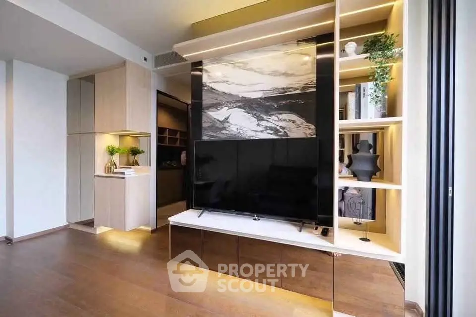 Modern living room with stylish shelving and large TV, featuring elegant decor and warm lighting.