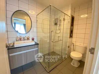 Modern bathroom with glass shower enclosure and stylish vanity in a contemporary apartment.