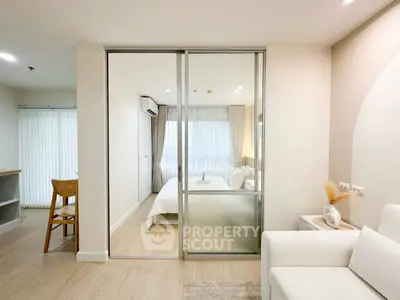 Modern living room with sliding glass doors leading to a cozy bedroom