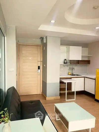 Modern open-layout kitchen and living area with sleek furniture and bright lighting.