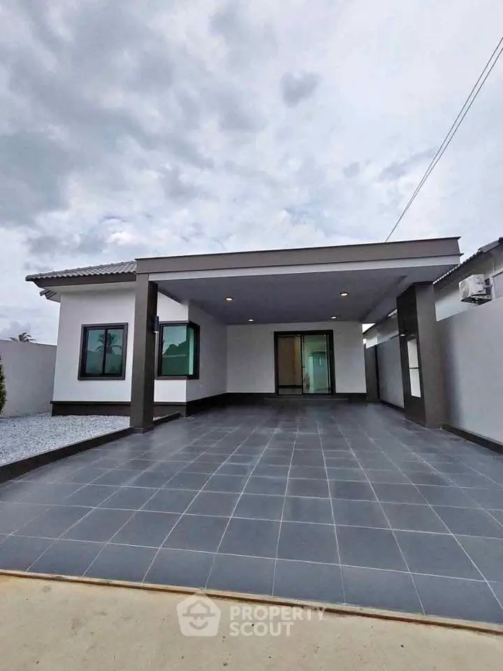 Modern single-story home with spacious driveway and sleek exterior design.