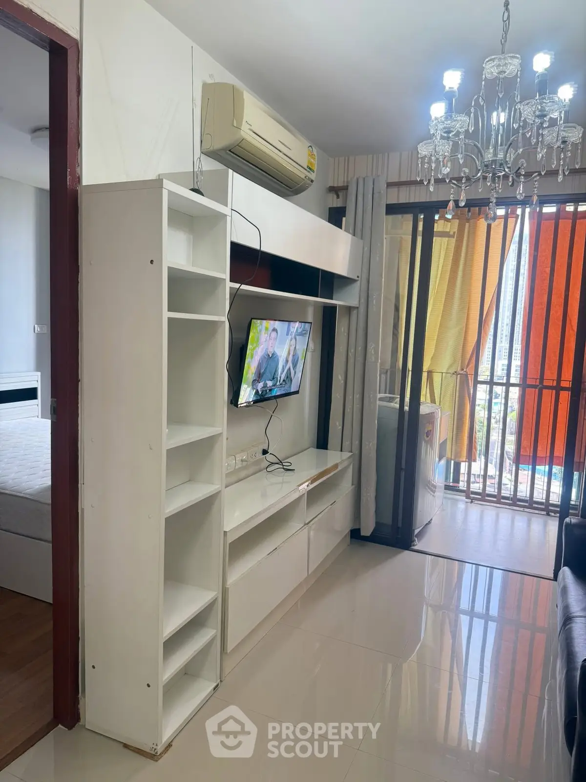 Modern living room with TV, air conditioning, and balcony access in stylish apartment.