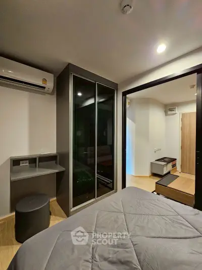 Modern bedroom with sleek design, featuring mirrored closet and air conditioning, perfect for urban living.