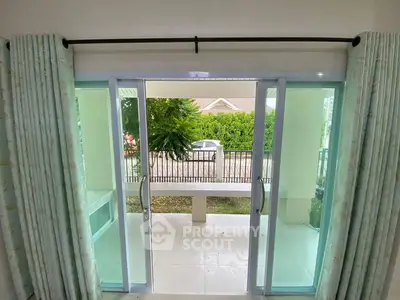 Spacious balcony view from living room with sliding glass doors and lush greenery.