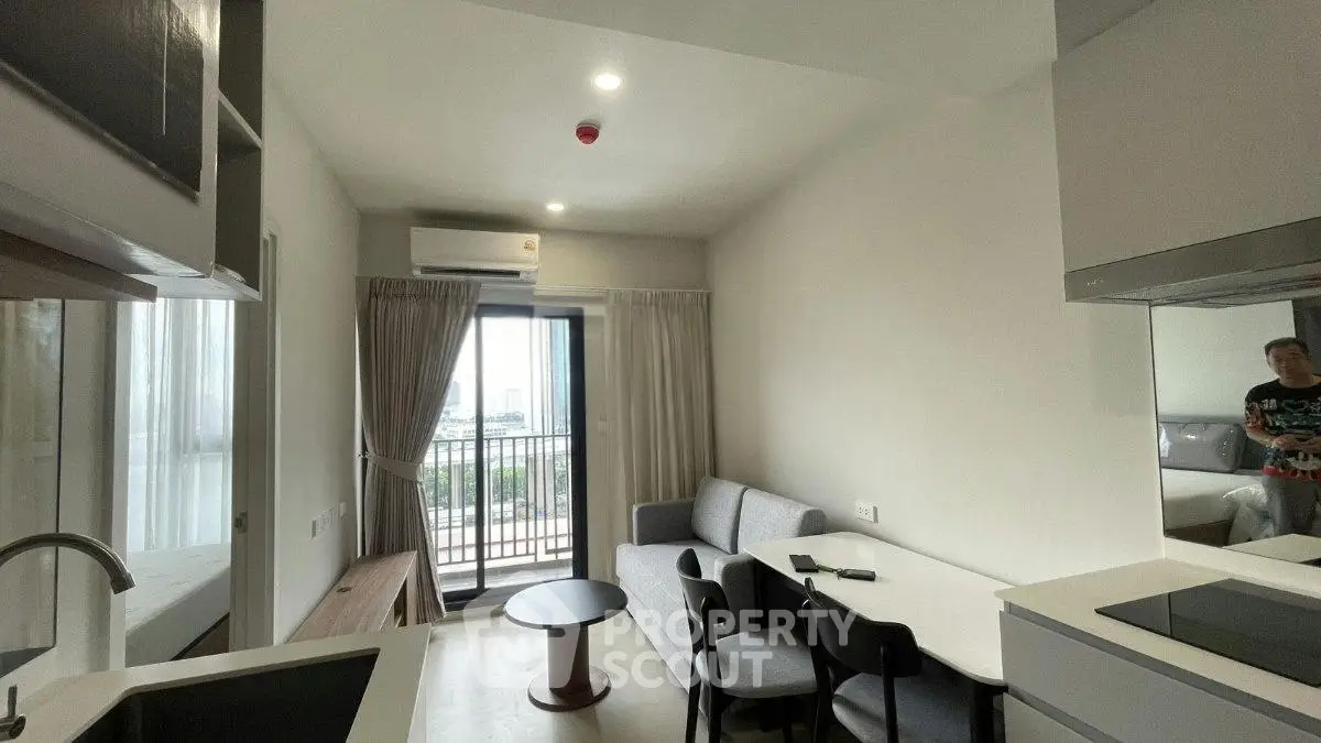 Modern living room with balcony view, featuring sleek furniture and open layout for a cozy atmosphere.
