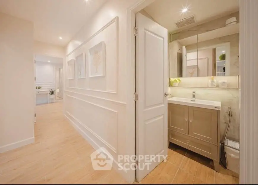Elegant hallway leading to a modern bathroom with stylish decor and ample lighting.