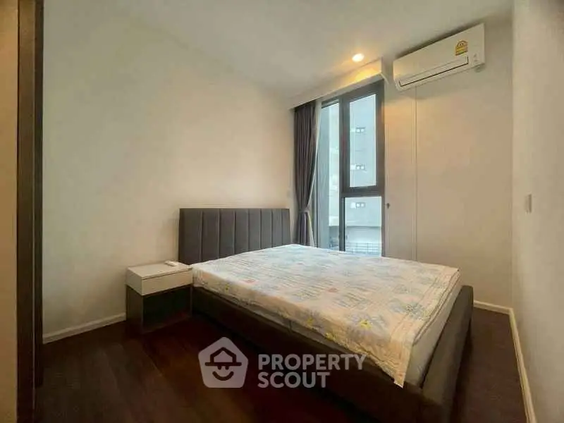 Modern bedroom with large window and air conditioning in a stylish apartment.