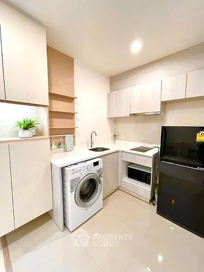 Modern kitchen with sleek appliances and stylish cabinetry, featuring a washing machine and refrigerator.