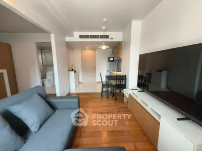 Modern living room with sleek furniture and open layout, featuring a cozy sofa and large TV.