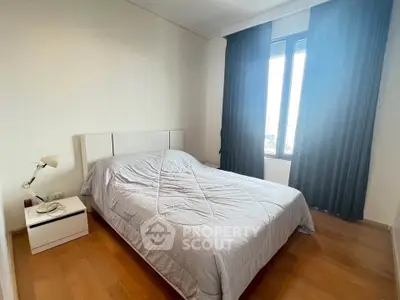 Cozy bedroom with modern decor and large window offering natural light