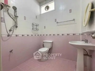 Charming pink-tiled bathroom with modern fixtures and natural light.