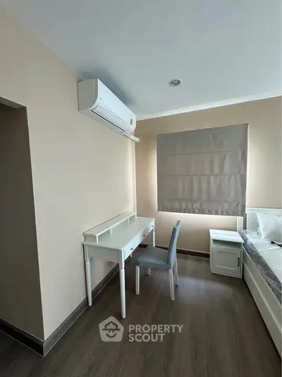 Modern bedroom with air conditioning and study desk, featuring minimalist design and neutral tones.