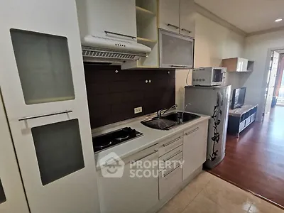 Modern kitchen with sleek cabinetry and appliances in a cozy apartment setting.