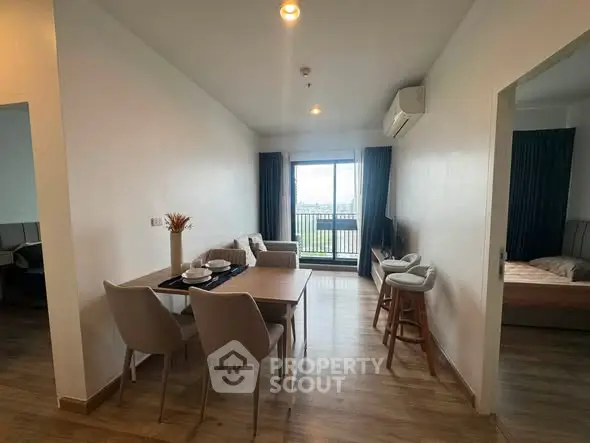 Modern apartment interior with open living and dining area, featuring stylish furniture and a balcony view.