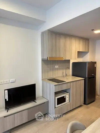 Modern kitchen with sleek cabinetry, compact appliances, and stylish decor in a contemporary apartment.