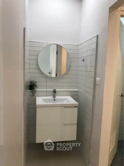 Modern minimalist bathroom with round mirror and sleek white vanity