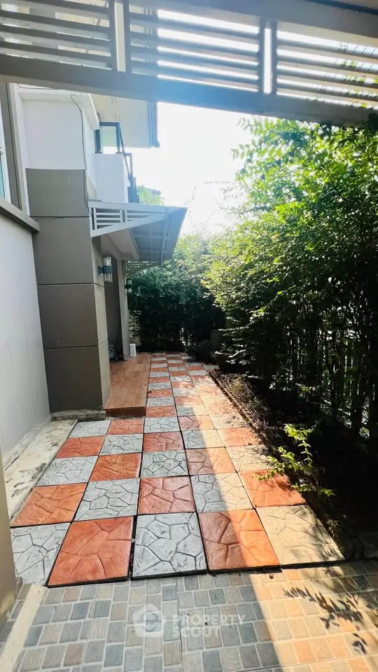 Charming garden pathway with colorful tiles and lush greenery in modern home exterior.