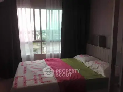 Cozy bedroom with large window offering city views, featuring a comfortable bed and stylish decor.