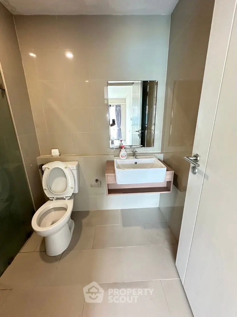 Modern bathroom with sleek fixtures and neutral tiles, featuring a toilet and stylish sink.
