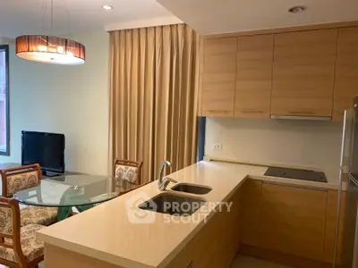 Modern kitchen with open layout and dining area, featuring sleek cabinetry and elegant lighting.