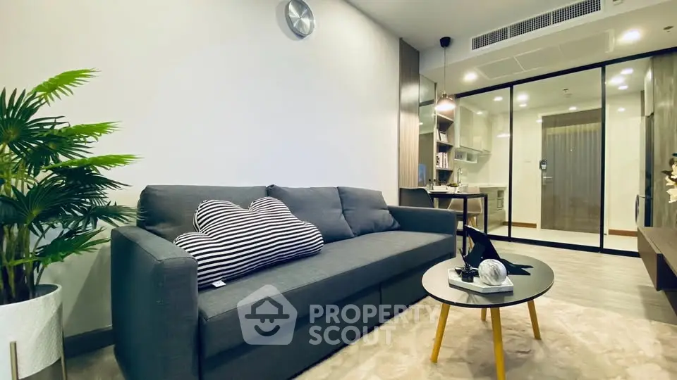 Modern living room with stylish decor and open layout, featuring a cozy sofa and sleek glass partition.