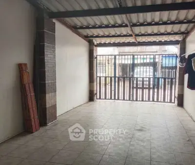 Spacious garage with tiled flooring and metal gate, ideal for secure parking or storage.