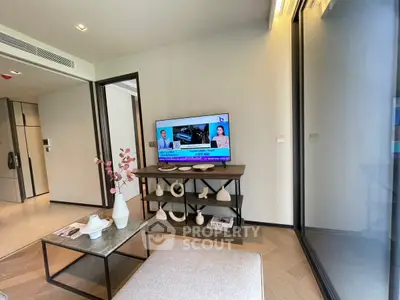 Modern living room with TV, stylish decor, and large windows for natural light.